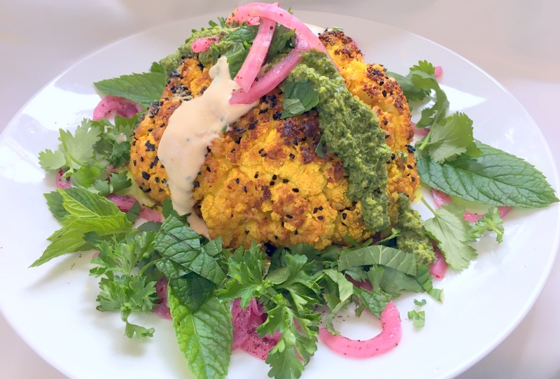 Whole Roasted Cauliflower with Zhoug, Tahini Sauce, Sumac Onions and Herbs